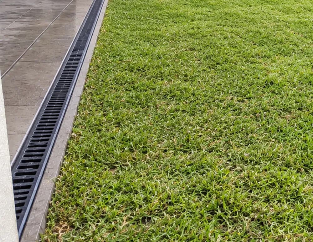 The same style of backyard with recovered lawn and a channel drain running along the edge