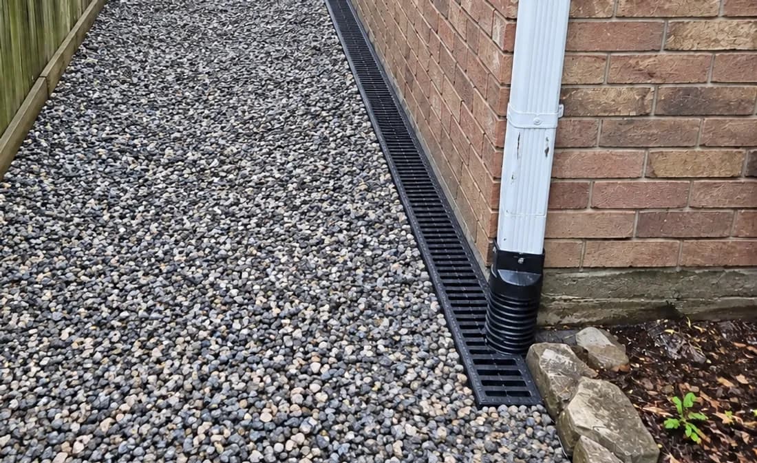The same style of side yard finished with a channel drain along the wall and a gravel surface